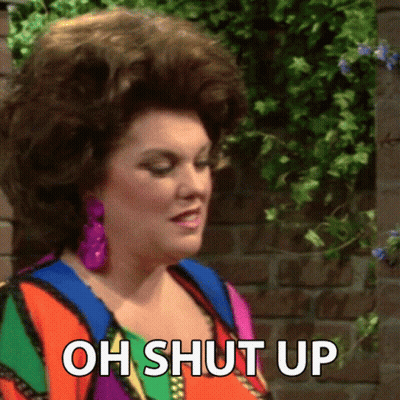 A Woman Is Standing In Front Of A Brick Wall And Says " Oh Shut Up " GIF