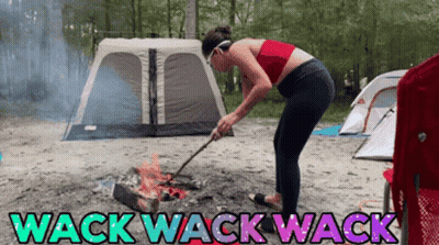A Woman Is Standing In Front Of A Campfire With The Words Wack Wack Wack On The Bottom GIF