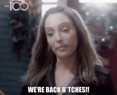 A Woman Is Standing In Front Of A Christmas Tree And Saying `` We 'Re Back Bitches ! '' GIF