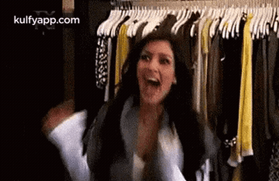 A Woman Is Standing In Front Of A Closet Filled With Clothes And Laughing . GIF