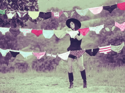 A Woman Is Standing In Front Of A Clothesline With Pink Underwear Hanging From It GIF
