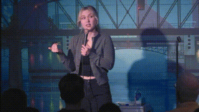 A Woman Is Standing In Front Of A Crowd Holding A Microphone And Giving A Speech . GIF