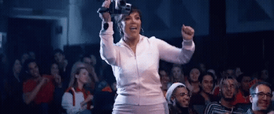 A Woman Is Standing In Front Of A Crowd Holding A Video Game Controller . GIF