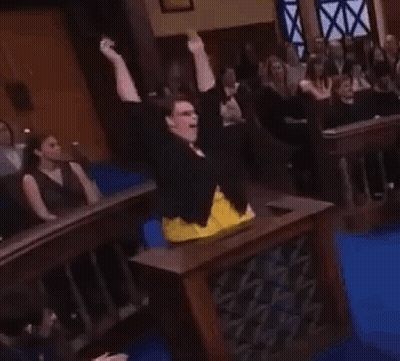 A Woman Is Standing In Front Of A Crowd In A Courtroom . GIF