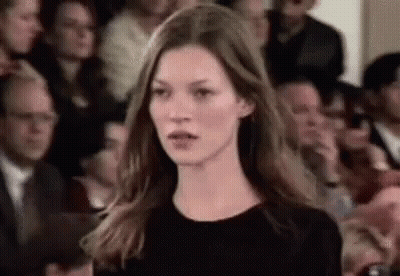 A Woman Is Standing In Front Of A Crowd Of People . GIF