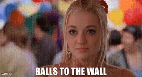 A Woman Is Standing In Front Of A Crowd Of People With Balloons And Says Balls To The Wall . GIF