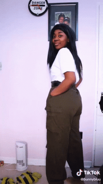 A Woman Is Standing In Front Of A Danger Zone Sign GIF