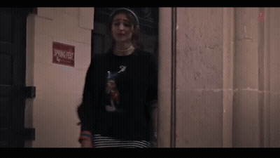 A Woman Is Standing In Front Of A Door In A Dark Room . GIF