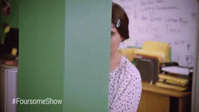 A Woman Is Standing In Front Of A Green Wall With The Words Foursomeshow Written On It GIF