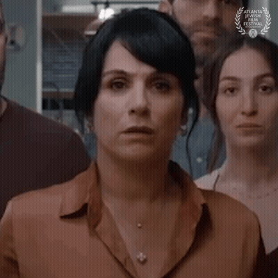 A Woman Is Standing In Front Of A Group Of People With A Laurel Wreath On Her Neck . GIF