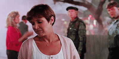 A Woman Is Standing In Front Of A Group Of People With A Man In A Military Uniform Standing Behind Her . GIF