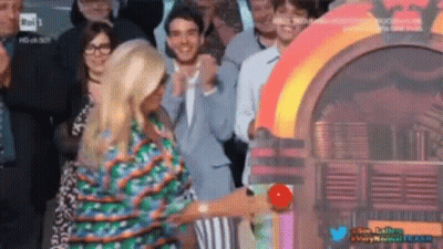 A Woman Is Standing In Front Of A Jukebox In A Crowd Of People GIF