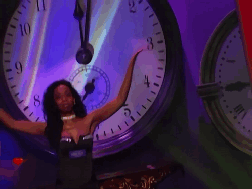 A Woman Is Standing In Front Of A Large Clock With The Word Net On The Bottom GIF