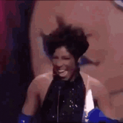 A Woman Is Standing In Front Of A Microphone And Laughing . GIF