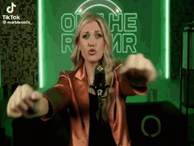 A Woman Is Standing In Front Of A Microphone With Her Arms Outstretched GIF