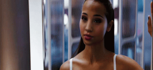 A Woman Is Standing In Front Of A Mirror Looking At Herself . GIF