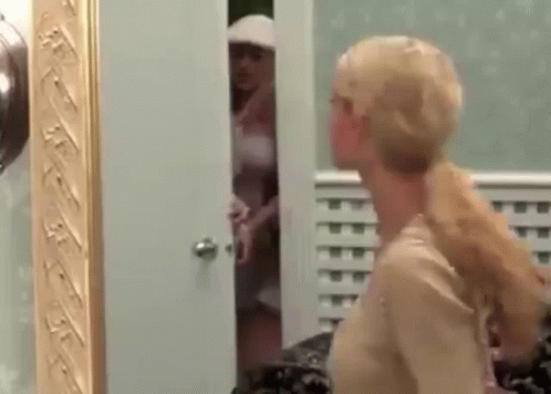 A Woman Is Standing In Front Of A Mirror Looking At Herself In The Mirror . GIF