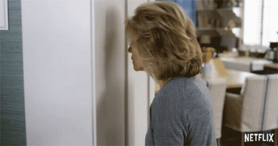 A Woman Is Standing In Front Of A Netflix Sign GIF