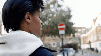 A Woman Is Standing In Front Of A No Entry Sign GIF