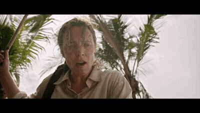 A Woman Is Standing In Front Of A Palm Tree Holding A Stick GIF