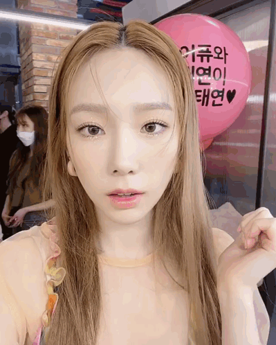 A Woman Is Standing In Front Of A Pink Balloon That Says ' I Love You ' On It GIF