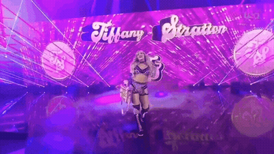 A Woman Is Standing In Front Of A Purple Wall That Says Tiffany Stratton GIF
