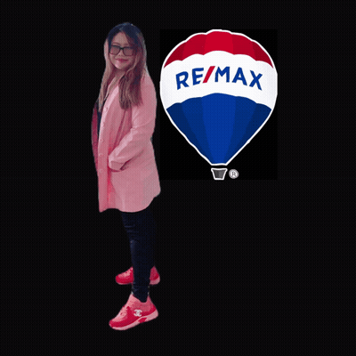 A Woman Is Standing In Front Of A Re/max Logo GIF