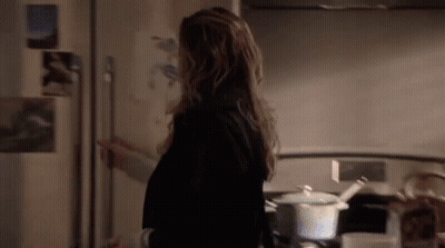 A Woman Is Standing In Front Of A Refrigerator In A Kitchen . GIF