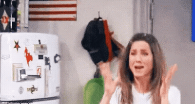A Woman Is Standing In Front Of A Refrigerator With Stickers On It And Crying . GIF