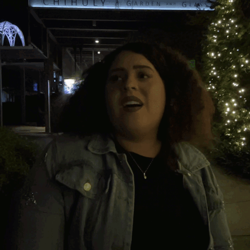 A Woman Is Standing In Front Of A Sign That Says Alright GIF
