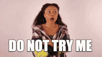 A Woman Is Standing In Front Of A Sign That Says Do Not Try Me GIF