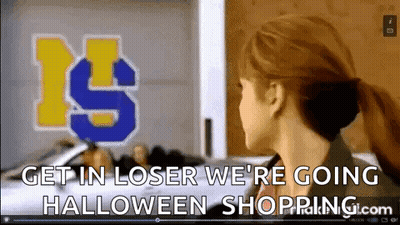 A Woman Is Standing In Front Of A Sign That Says `` Get In Loser We 'Re Going Halloween Shopping.com '' GIF
