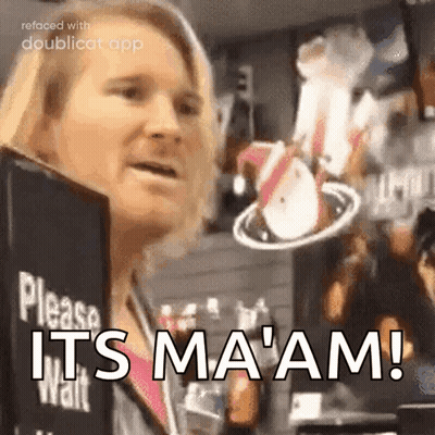 A Woman Is Standing In Front Of A Sign That Says Please Wait It 'S Ma 'Am GIF