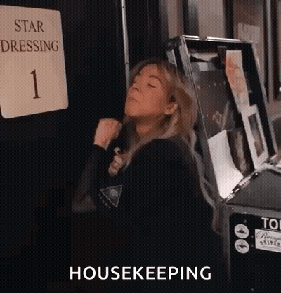 A Woman Is Standing In Front Of A Sign That Says Star Dressing 1 And A Box That Says Housekeeping . GIF
