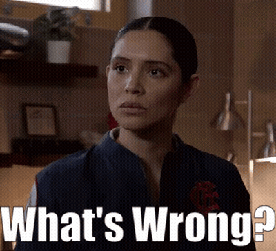A Woman Is Standing In Front Of A Sign That Says " What 'S Wrong " GIF