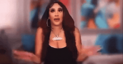 A Woman Is Standing In Front Of A Television With Her Arms Outstretched And A Necklace On Her Neck . GIF