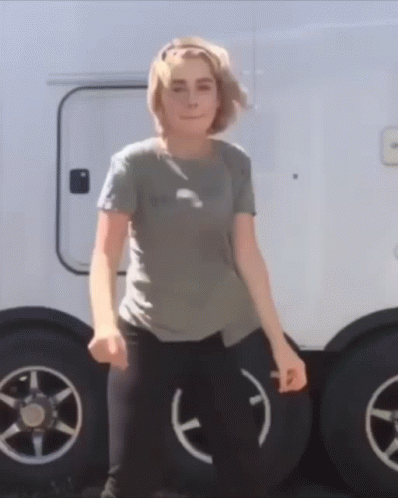 A Woman Is Standing In Front Of A Trailer With A Smiley Face On The Tire GIF