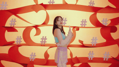 A Woman Is Standing In Front Of A Wall Of Hashtags GIF