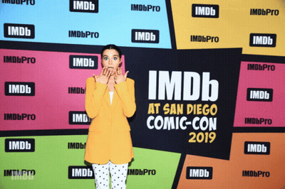 A Woman Is Standing In Front Of A Wall That Says Imdb At San Diego Comic-Con 2019 GIF