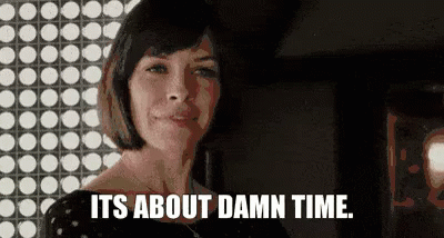 A Woman Is Standing In Front Of A Wall With Polka Dots And Says `` It 'S About Damn Time . '' GIF