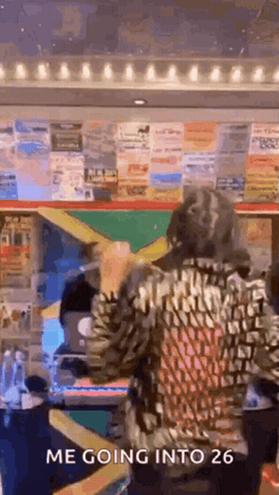 A Woman Is Standing In Front Of A Wall With Posters On It . GIF