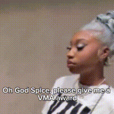 A Woman Is Standing In Front Of A Wall With The Words `` Oh God Spice , Please Give Me A Vma Award '' . GIF