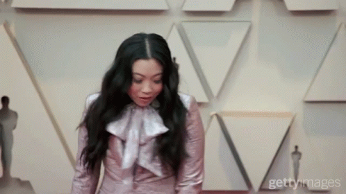 A Woman Is Standing In Front Of A Wall With Triangles On It GIF