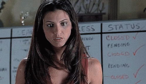 A Woman Is Standing In Front Of A White Board With The Word Status Written On It . GIF