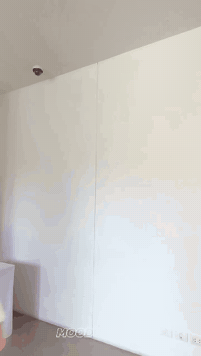 A Woman Is Standing In Front Of A White Wall And Smiling GIF