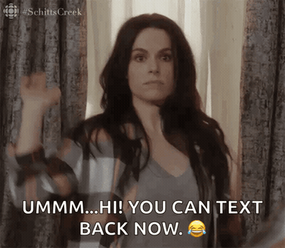 A Woman Is Standing In Front Of A Window And Says " Ummm Hi ! You Can Text Back Now " GIF