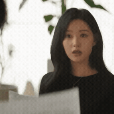 A Woman Is Standing In Front Of A Window Holding A Piece Of Paper . GIF
