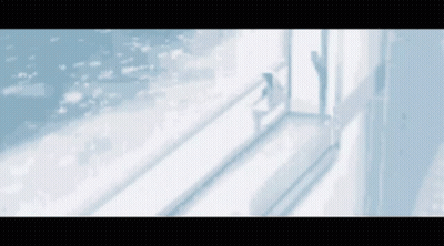A Woman Is Standing In Front Of A Window Looking Out At The Ocean . GIF