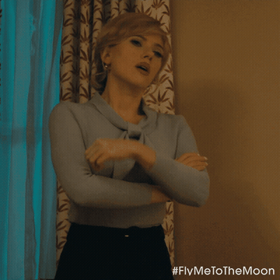 A Woman Is Standing In Front Of A Window With Her Arms Crossed And #Flymetothemoon Written On The Bottom GIF