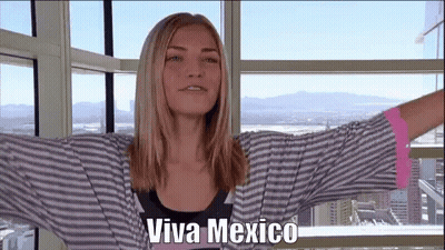 A Woman Is Standing In Front Of A Window With Her Arms Outstretched And The Words Viva Mexico On Her Face . GIF